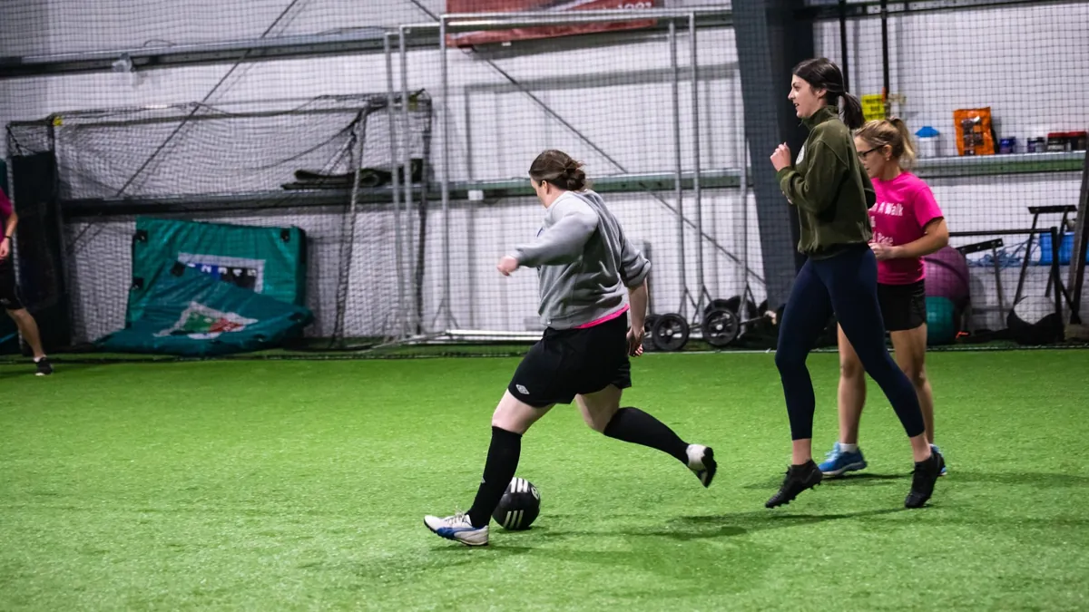 Players chasing the ball on an indoor turf field