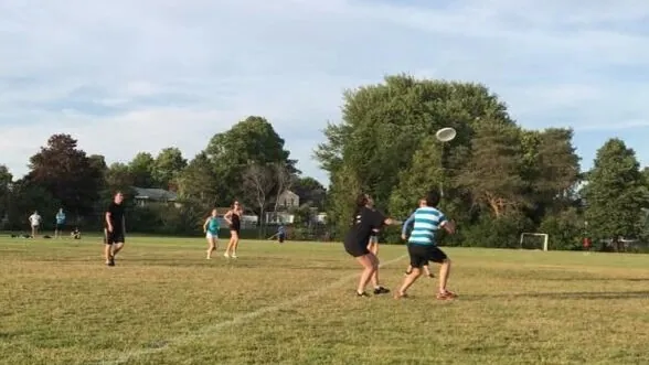 Ultimate frisbee on an open grass field, the disc in the air