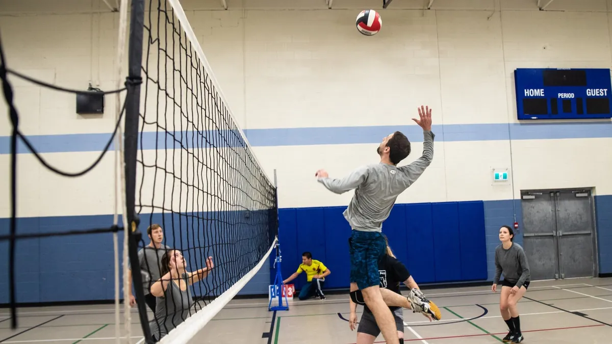A player jumping to spike at the net during an indoor volleyball game